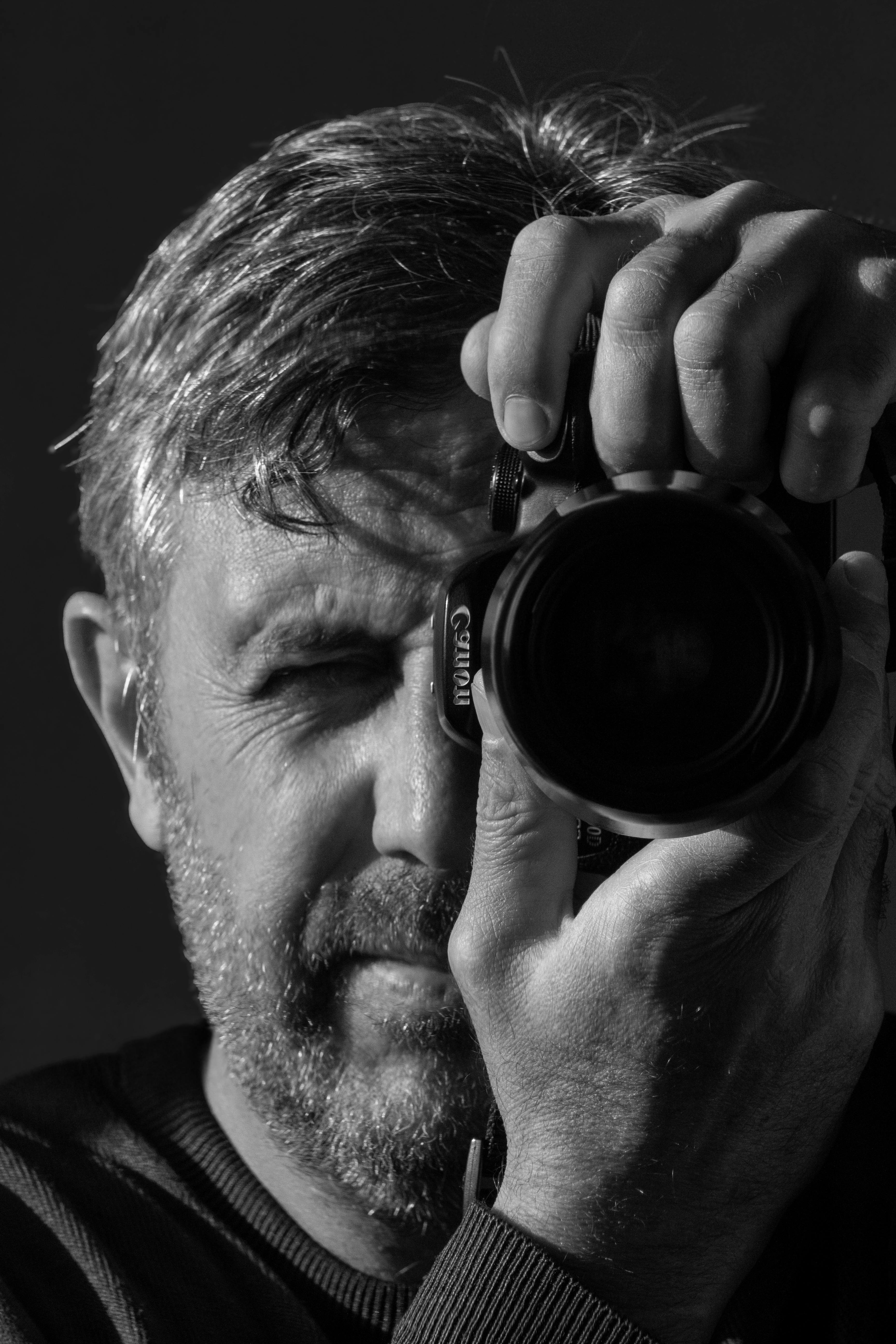 Monochrome close-up of a male photographer taking a photo, highlighting focus and concentration.