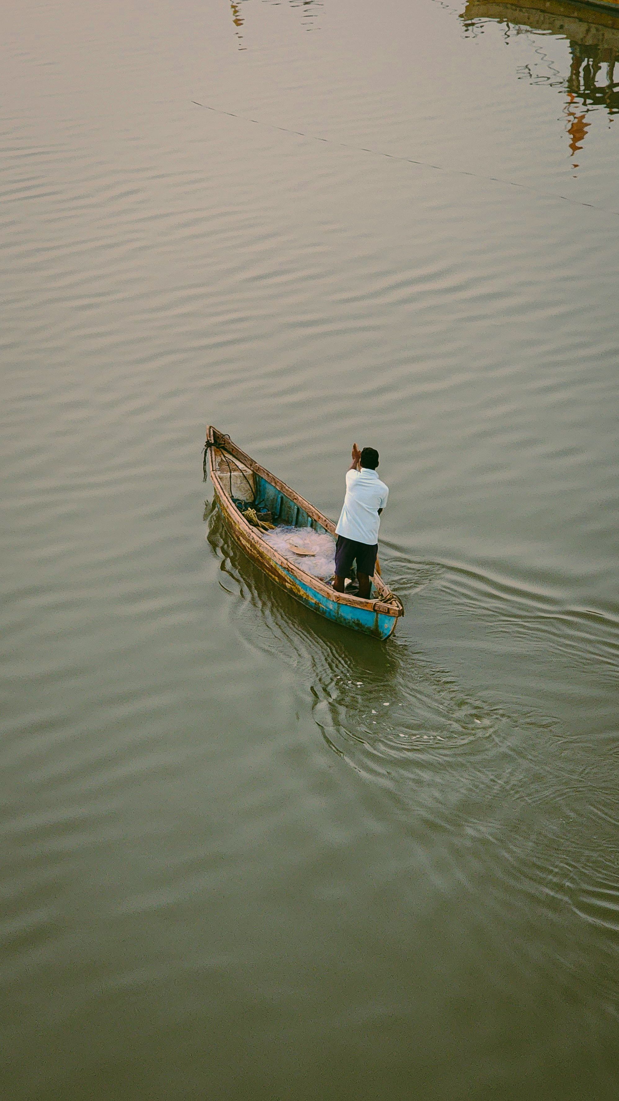 Man Rowing a Wooden Boat on Tranquil River · Free Stock Photo