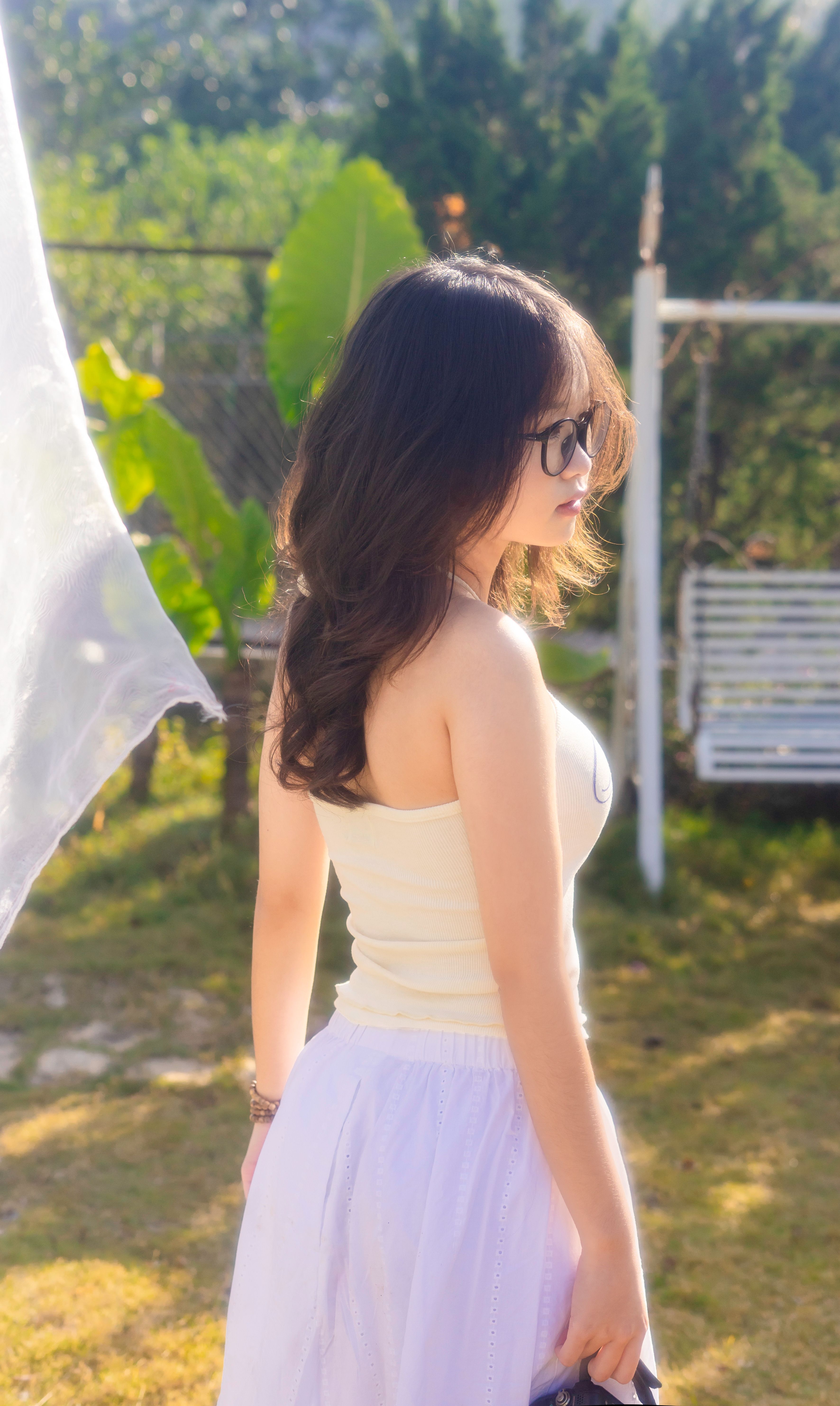Young woman in white dress with long hair enjoying the sun outdoors.