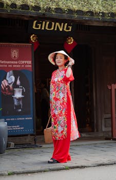 A woman in a vibrant Áo Dài poses outdoors in Hội An, Vietnam, showcasing traditional fashion and culture.