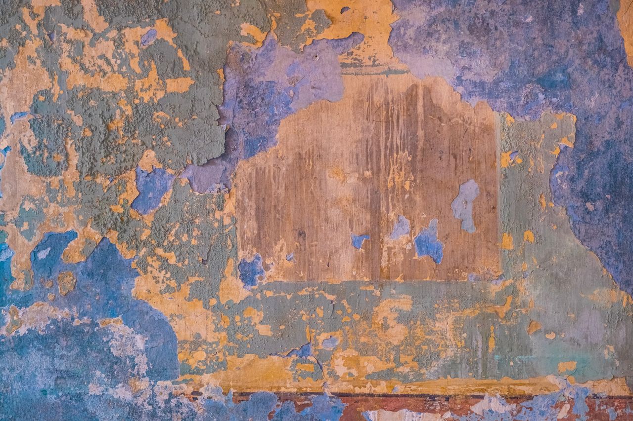 detailed texture of peeling paint with vibrant colors on an old wall