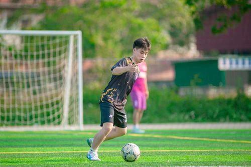 Free A young athlete skillfully maneuvers a soccer ball on a vibrant outdoor field in Hà Nội, Việt Nam. Stock Photo