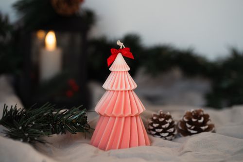Free A pink Christmas tree-shaped candle with festive decor, evoking a cozy holiday atmosphere. Stock Photo