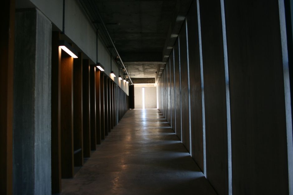 A dark industrial corridor with geometric lines and subtle lighting creating a moody atmosphere.