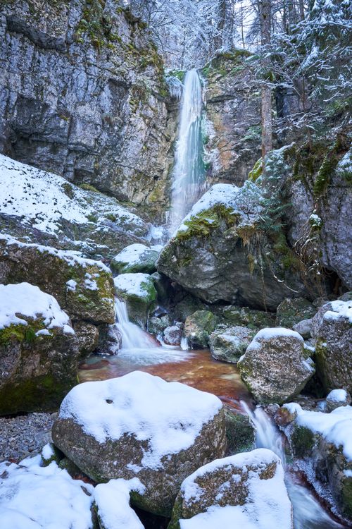 Free Snow-covered rocks and a serene waterfall in Bayern, Germany, captured in winter. Stock Photo