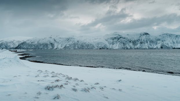 Frozen landscape in winter with snow-covered mountains by the Arctic coastline, Norway.