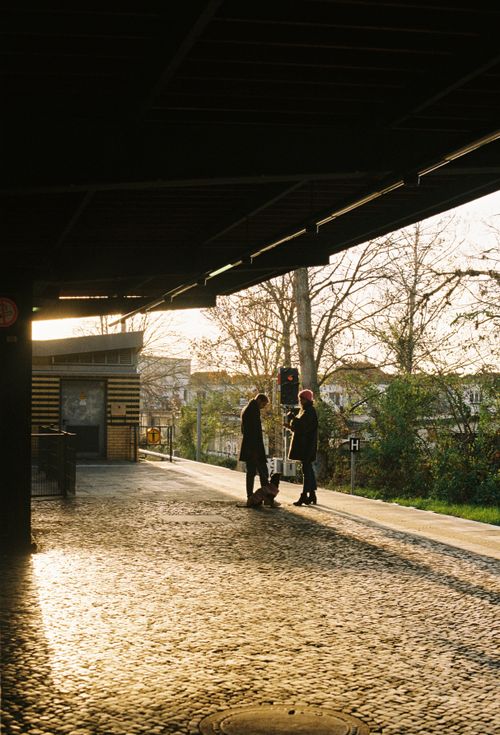 Free Two people silhouetted at an outdoor train station platform as the sun sets. Stock Photo
