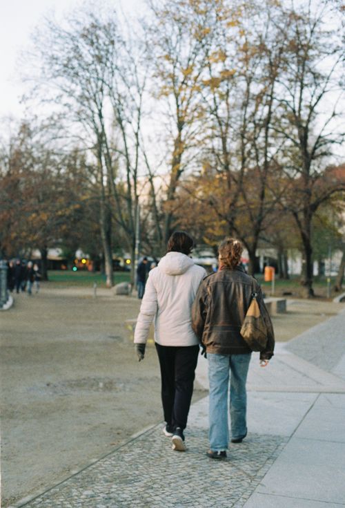 Free Two individuals walk through a serene park on an autumn day, surrounded by bare trees. Stock Photo
