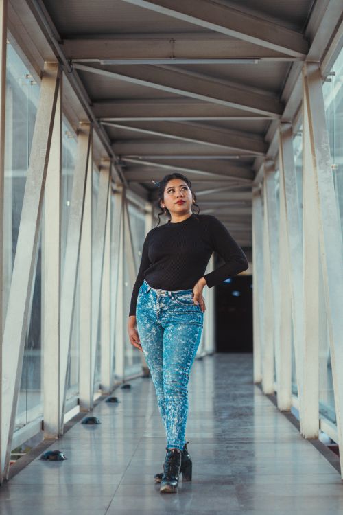 Free Elegant woman in a modern glass corridor, embodying urban fashion and confidence. Stock Photo