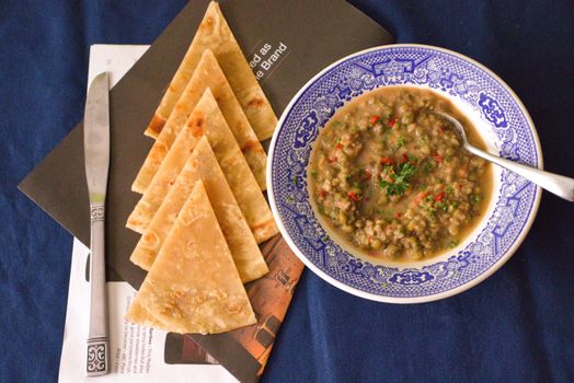 A flavorsome lentil soup paired with pita bread, captured in an appetizing overhead shot.