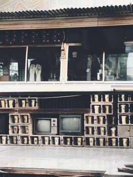 A retro display with vintage televisions, hand mannequins, and stacked pails on a brick wall.