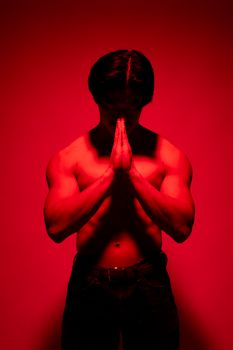 Studio photo of a muscular man in red lighting creating a dramatic atmospheric effect.