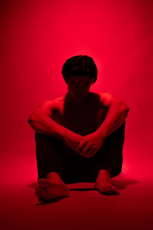 Free Artistic studio shot of a muscular man in red lighting, evoking emotion and strength. Stock Photo