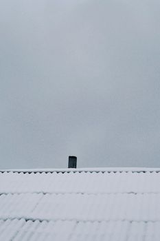 Minimalist winter scene of a snow-covered roof with chimney in Talgar, Kazakhstan.