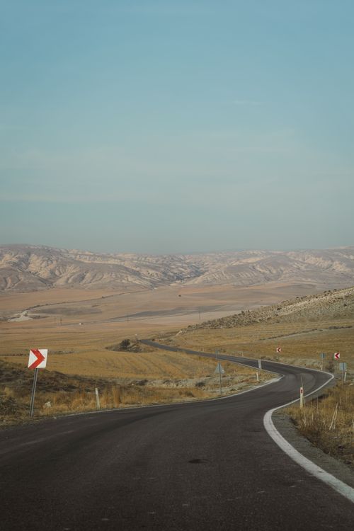 Free A winding road traverses the vast, rolling hills of Ankara's countryside, showcasing Turkey's striking natural beauty. Stock Photo