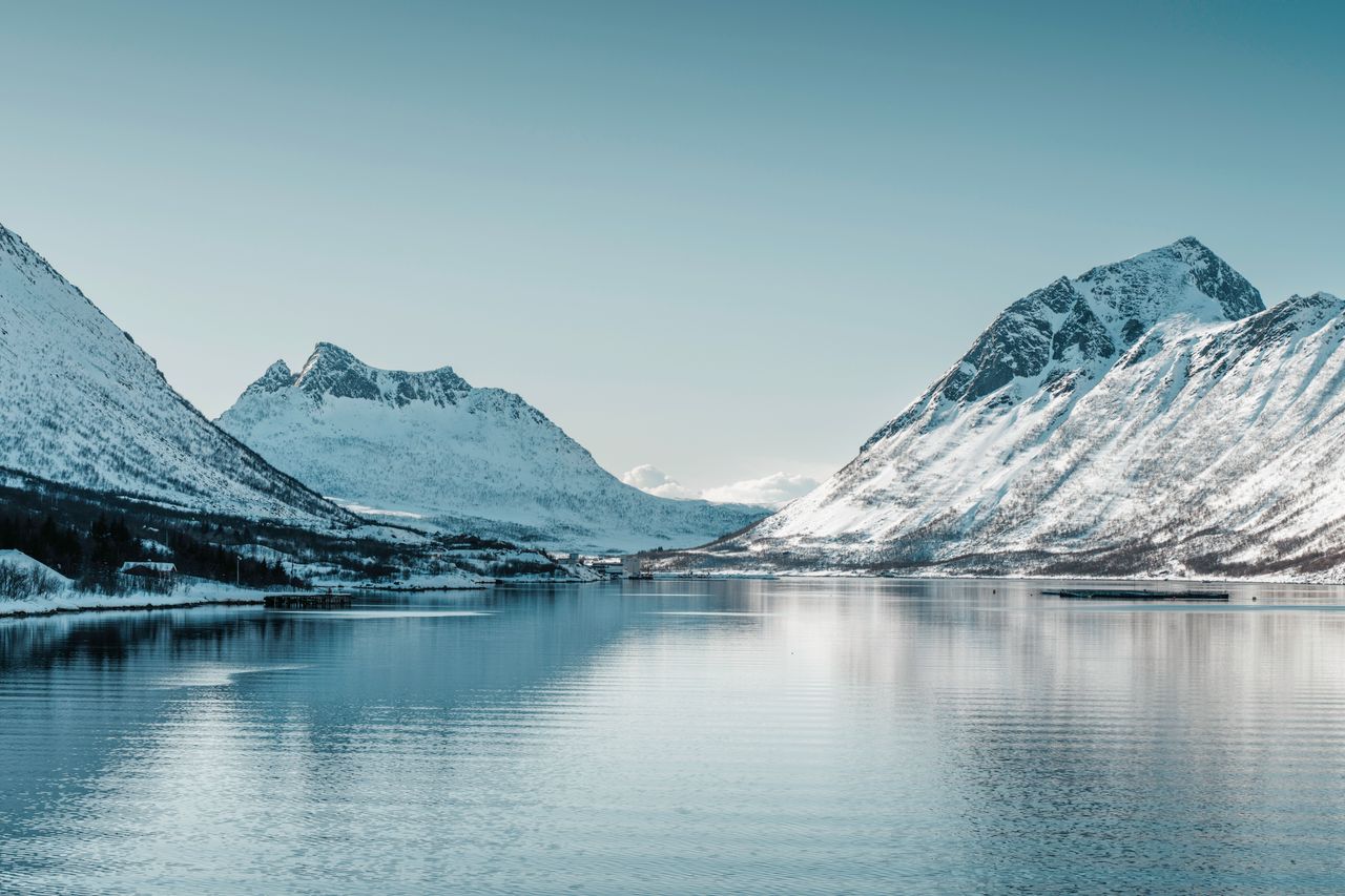 breathtaking view of snow covered mountains reflecting on calm arctic