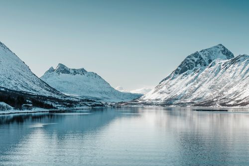 Free Breathtaking view of snow-covered mountains reflecting on calm Arctic waters. Stock Photo