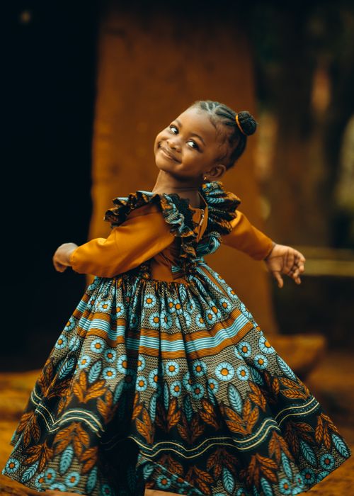 Free A smiling child in a colorful African dress enjoying an outdoor moment. Captured in Jos, Nigeria. Stock Photo