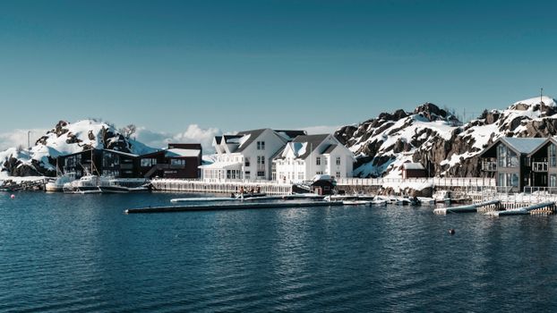 Explore a serene Arctic fjord resort surrounded by snow-covered mountains, showcasing tranquil beauty.