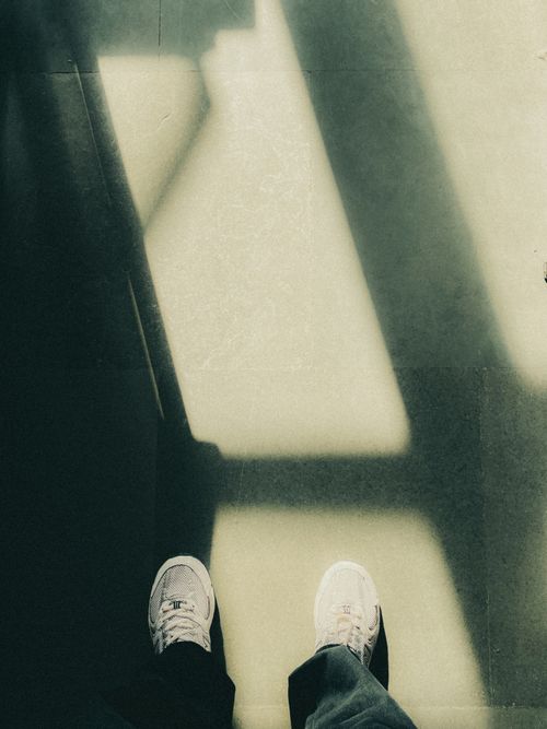 Free White sneakers casting geometric shadows on a sunlit floor, highlighting minimalist aesthetic. Stock Photo