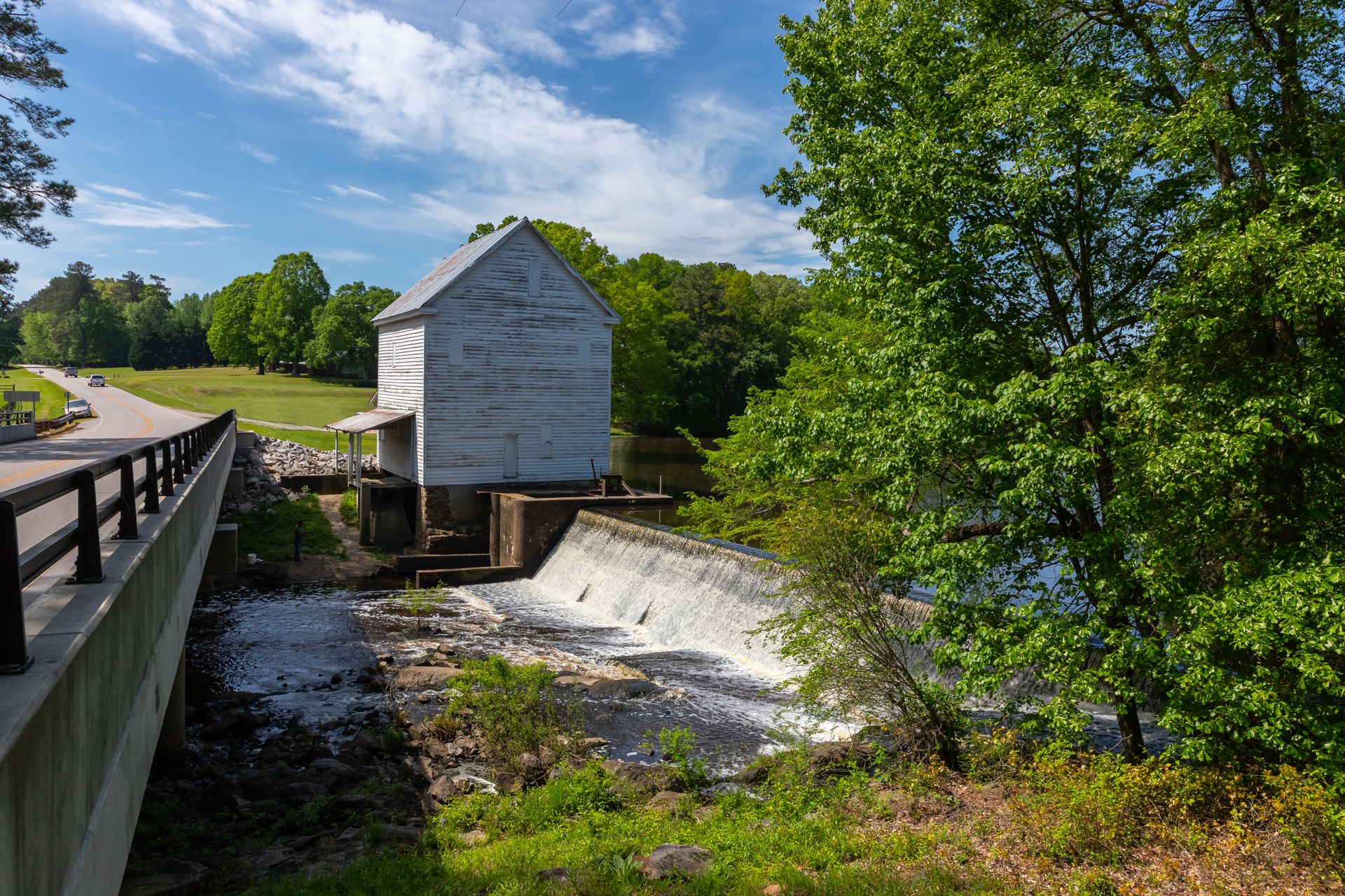A serene view of a historical mill and dam surrounded by lush greenery in North Carolina.