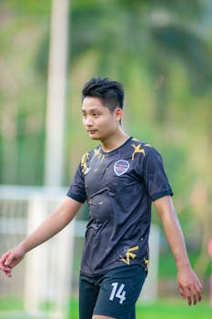 Young soccer player in black uniform on an outdoor field in Hanoi, Vietnam.