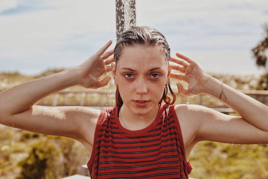A young woman in a striped top enjoys a refreshing outdoor shower at Panama City Beach.
