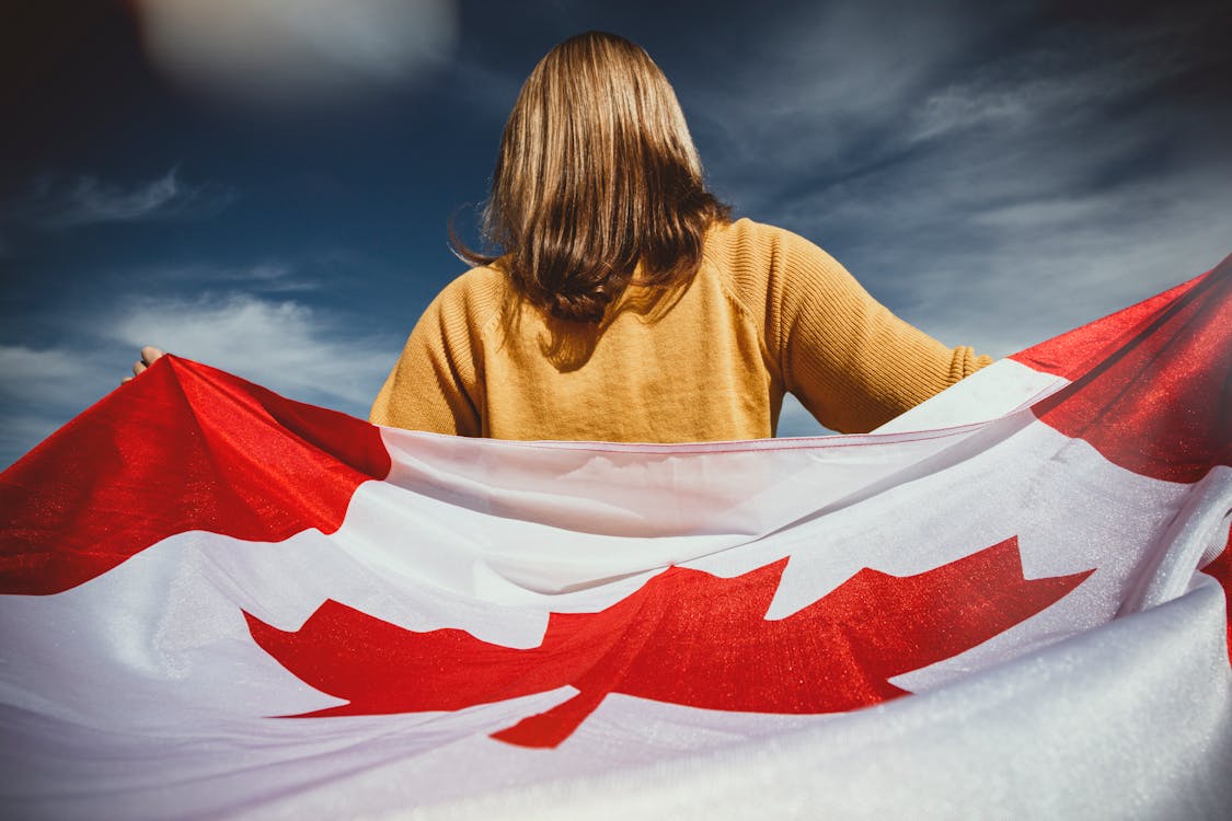 A woman proudly holds a Canadian flag, symbolizing her national pride and connection to Canada.