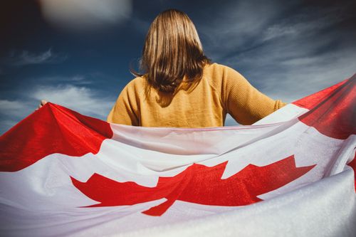 Free A woman holding the Canadian flag with mountains in Banff, Alberta, Canada. Stock Photo