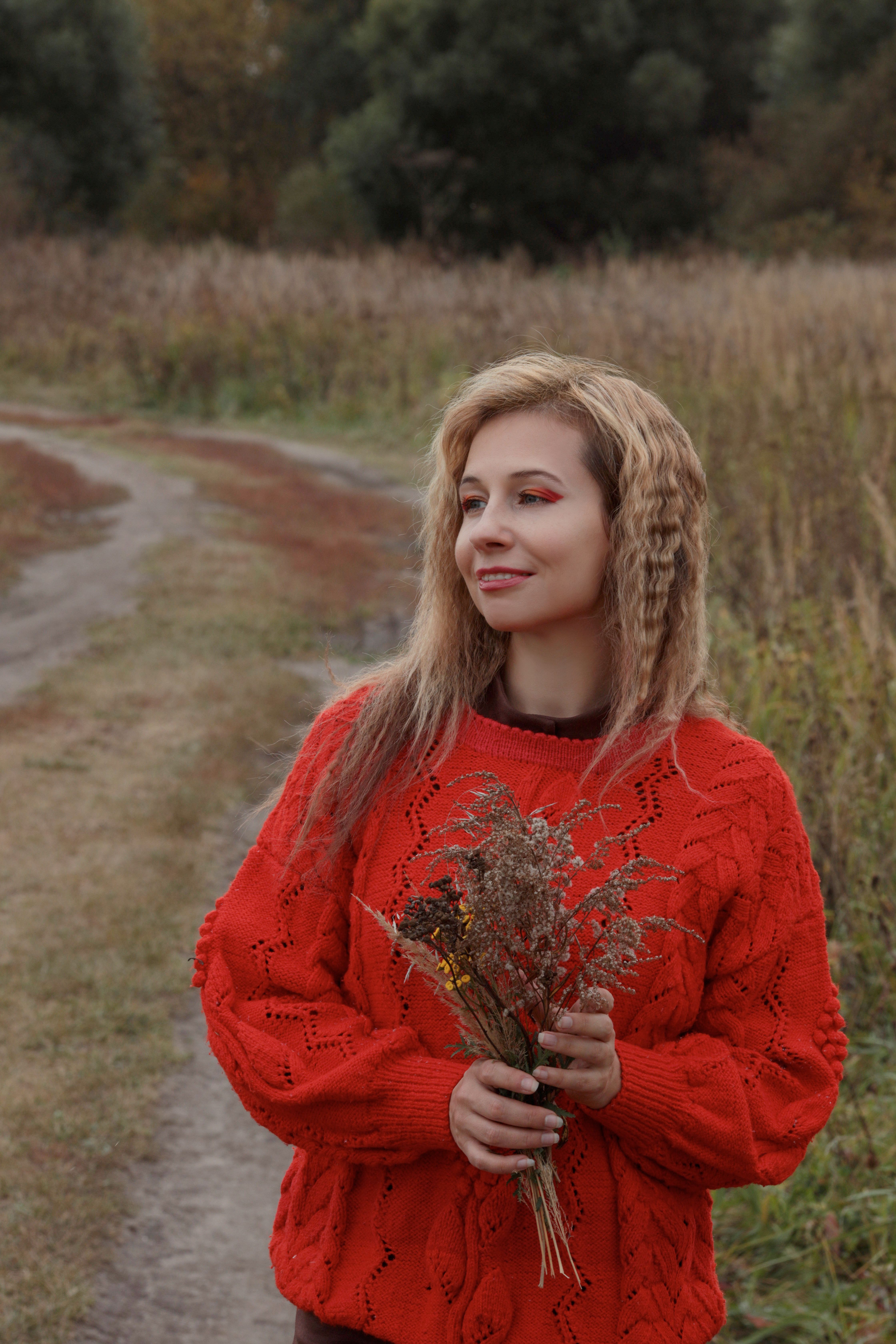 Woman in Red Sweater Holding Wildflowers Outdoors · Free Stock Photo