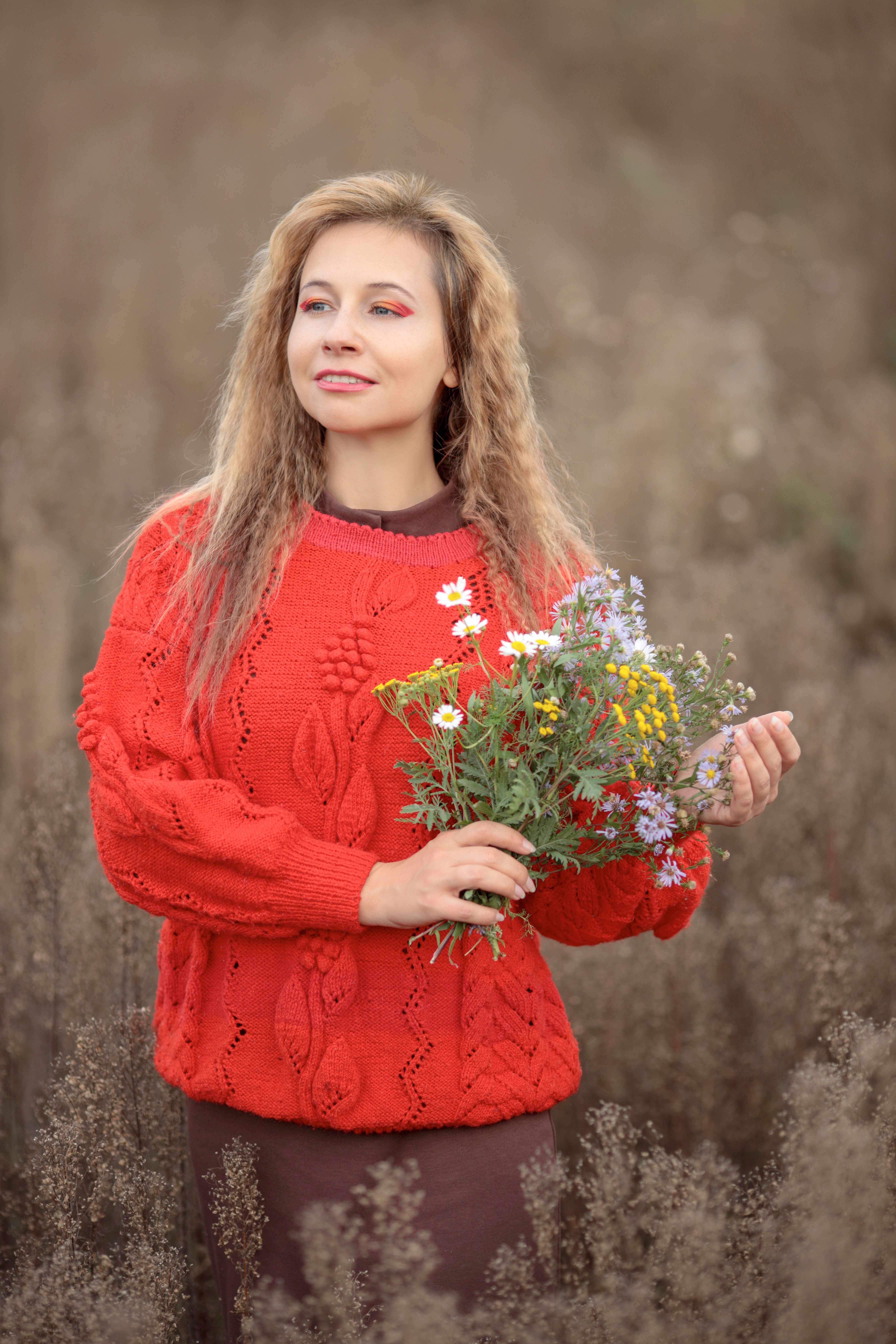 Woman in Red Sweater Holding Wildflowers Outdoors · Free Stock Photo