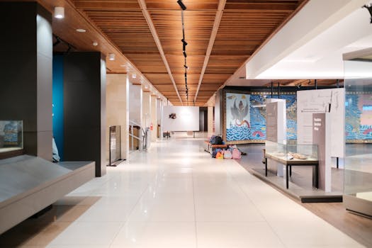 Bright museum hallway with exhibits and empty walkways, showcasing modern design.