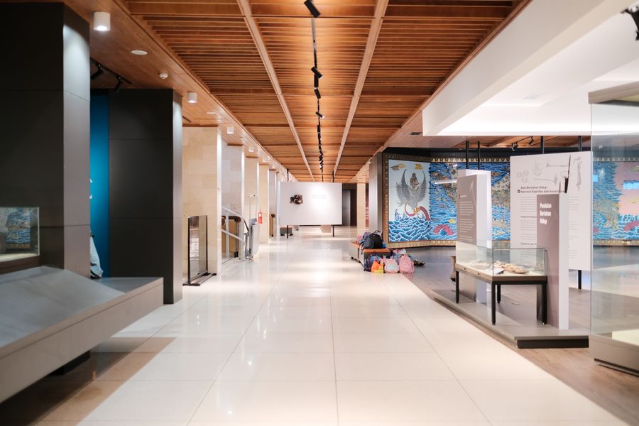 A bright museum hallway lined with exhibits and mostly empty walkways
