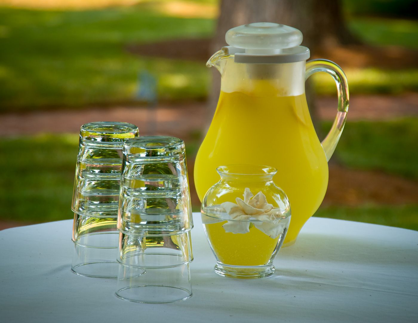 A frosty pitcher of fresh lemonade with glasses on a sunny table