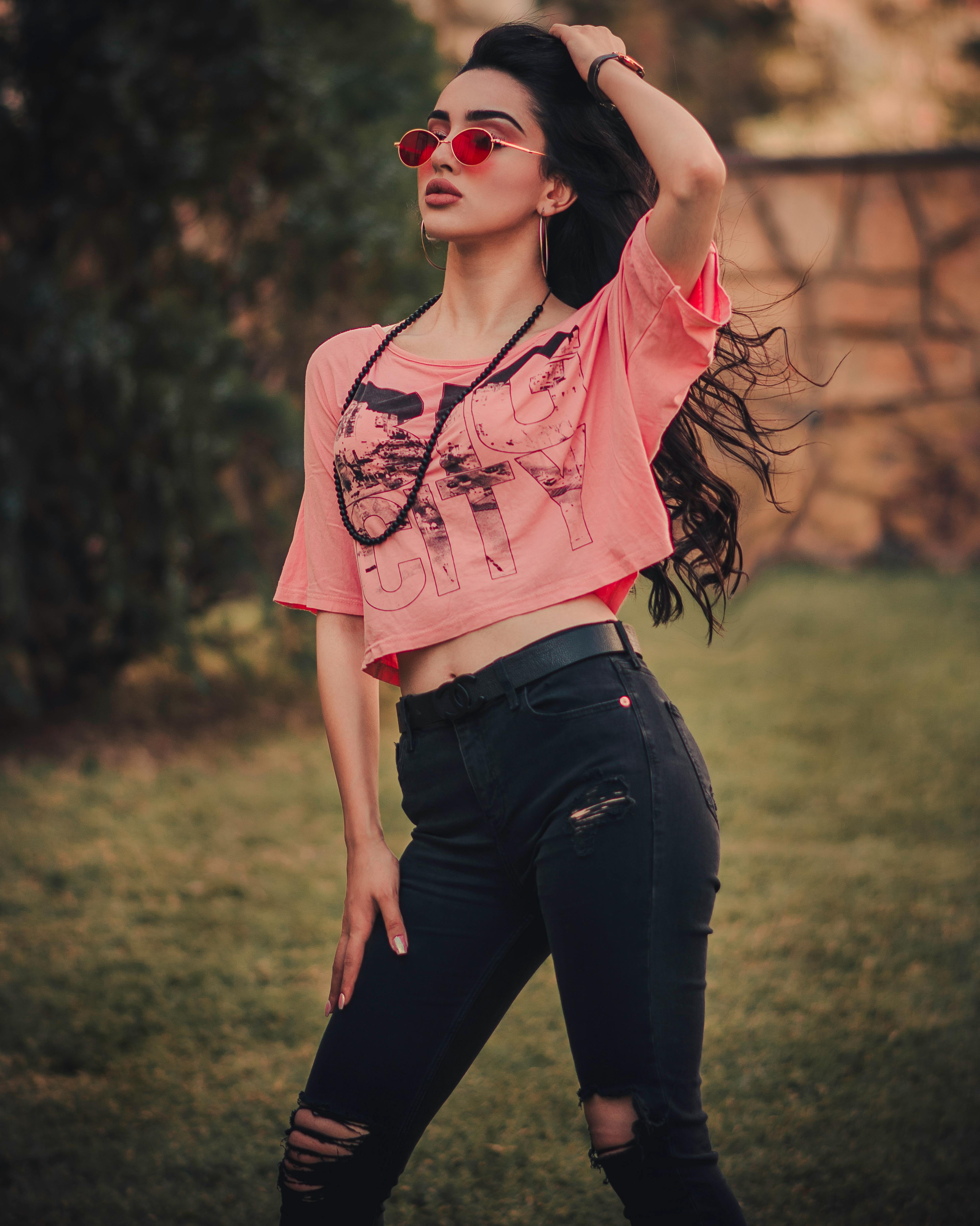 Woman in Black Crop Top and Denim Jeans Leaning by the Concrete Wall while  Looking Afar · Free Stock Photo