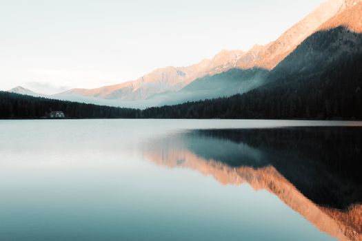 Peaceful morning view of a mountain lake with perfect reflections and misty ambiance.