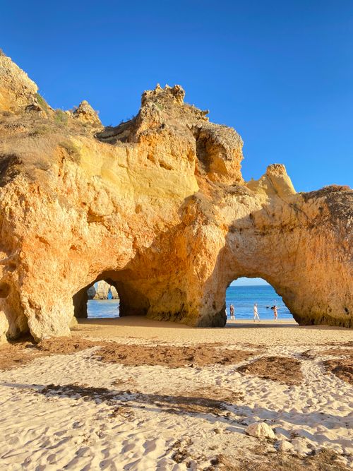Free Stunning rock formations and beach arches at Faro, Portugal, under a clear blue sky. Stock Photo