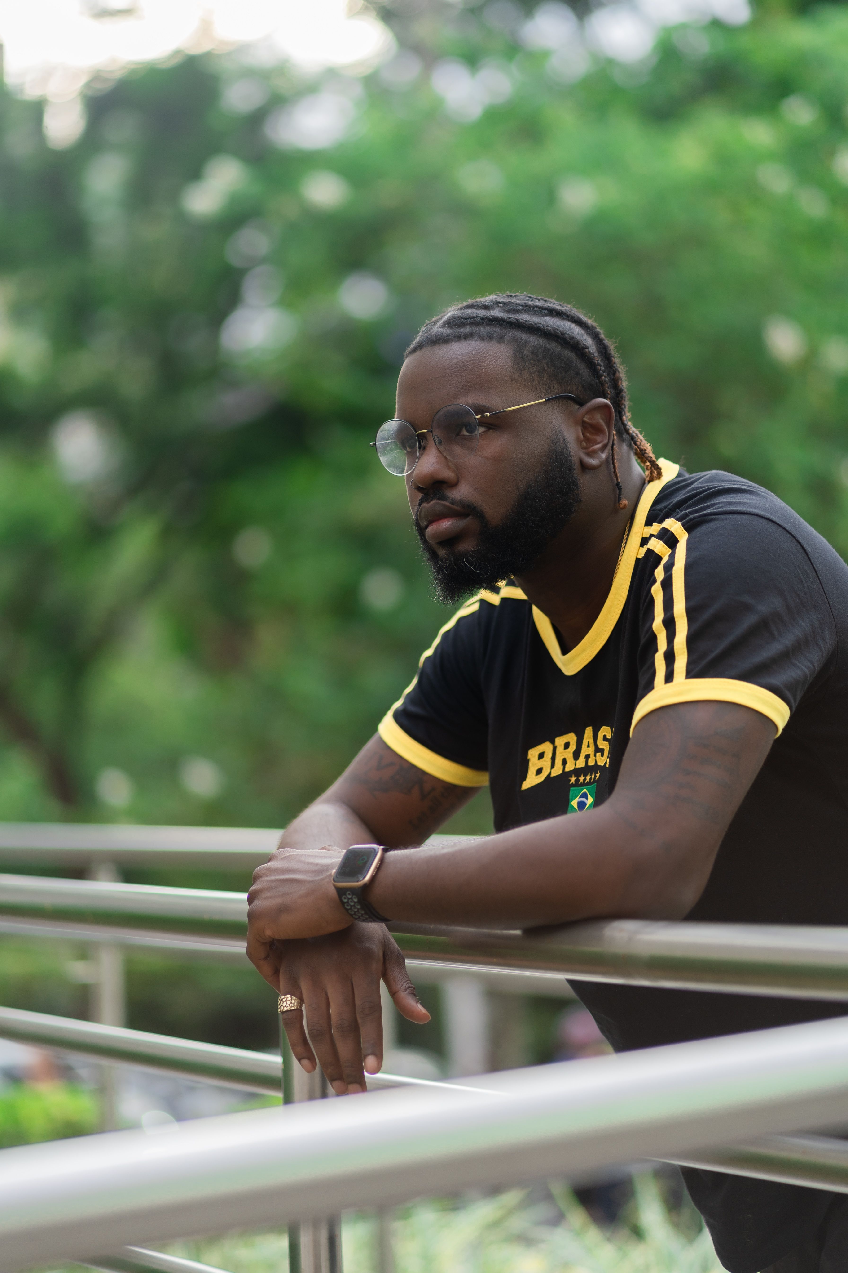 Casual portrait of a man in a Brazil sports jersey leaning on a railing outdoors.