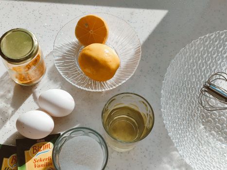 Sunlit kitchen scene with baking ingredients including lemons, eggs, and vanilla.