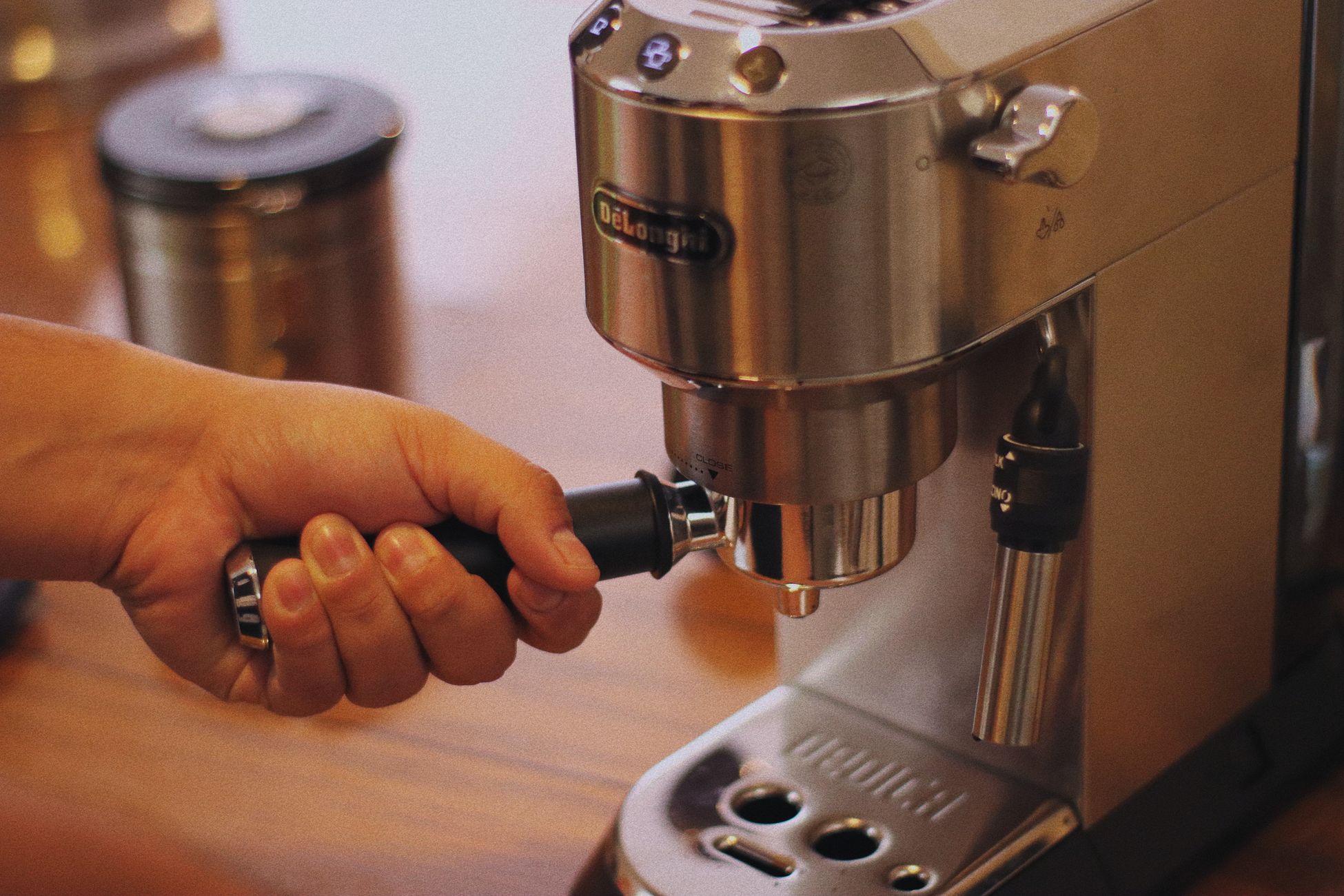 Person using a stainless steel espresso machine, making coffee.