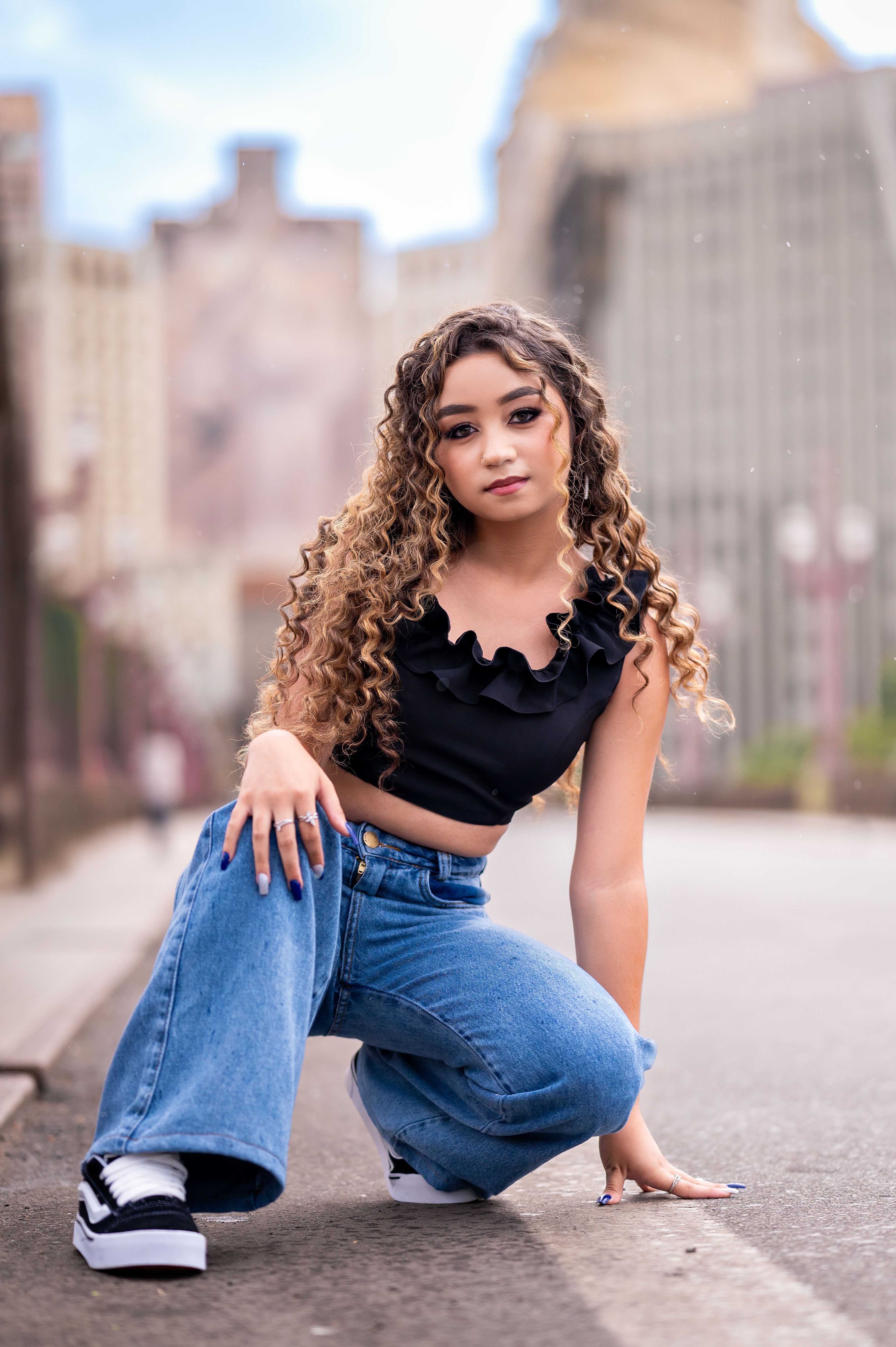Young Woman Posing on Urban Street with Curly Hair · Free Stock Photo