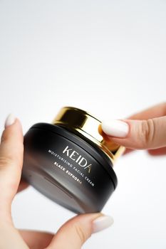 Moisturizing facial cream in a sleek black jar with gold lid, perfect for skincare routines.