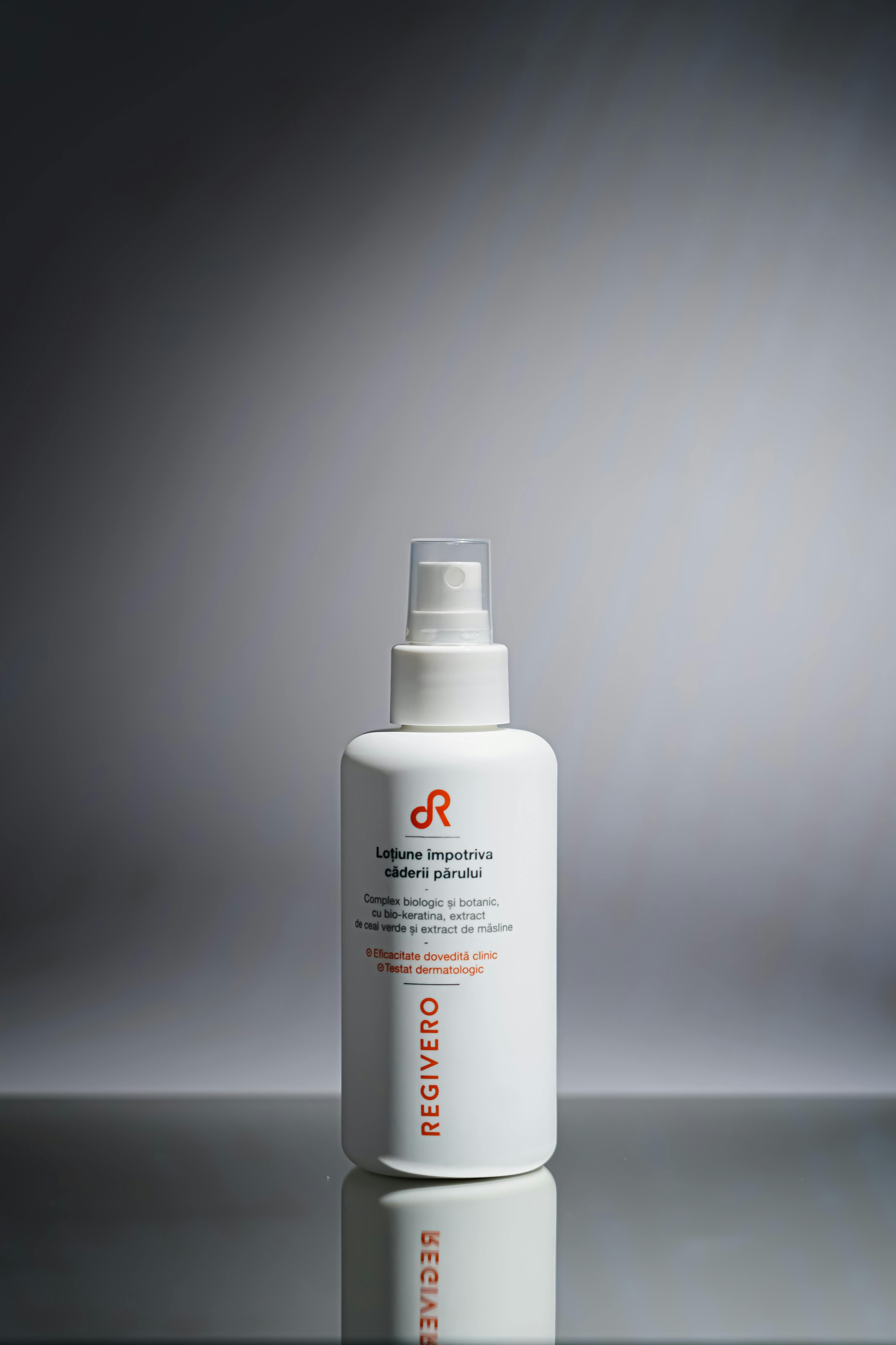 Minimalist shot of a hair care product bottle with branding on a gray background.