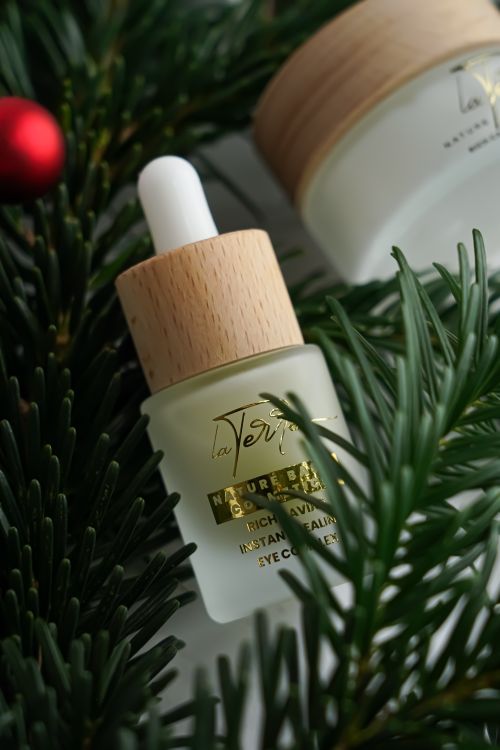 Free A bottle of natural eye cream amidst pine branches and festive decor, perfect for the holiday season. Stock Photo