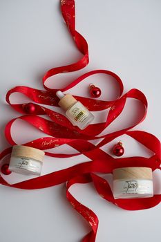 Festive skincare products arranged with red ribbon and ornaments.
