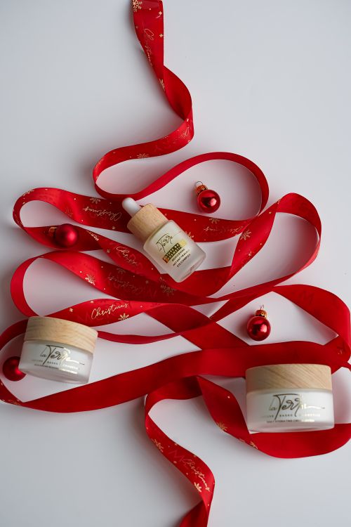 Free Festive skincare products arranged with red ribbon and ornaments. Stock Photo
