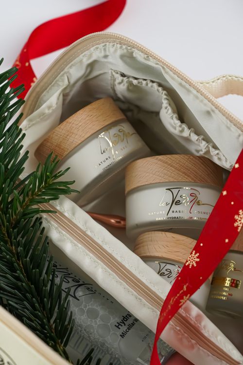 Free Natural skincare products in a festive gift set with red ribbon and greenery. Stock Photo