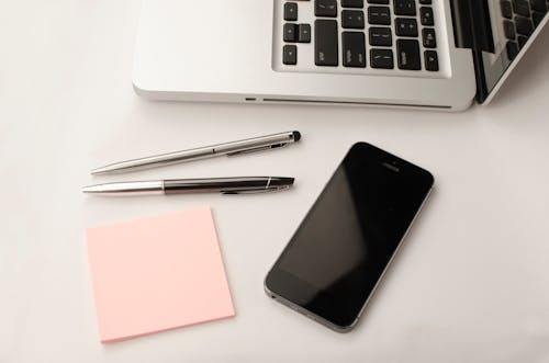 Free Space Gray Iphone 6 Beside Two Retractable Pens and Macbook Stock Photo