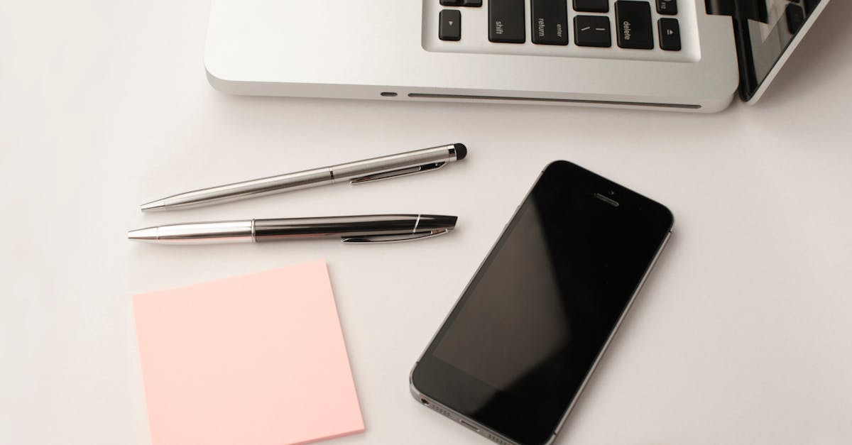 Clean and modern workspace featuring a laptop, smartphone, pens, and sticky notes.