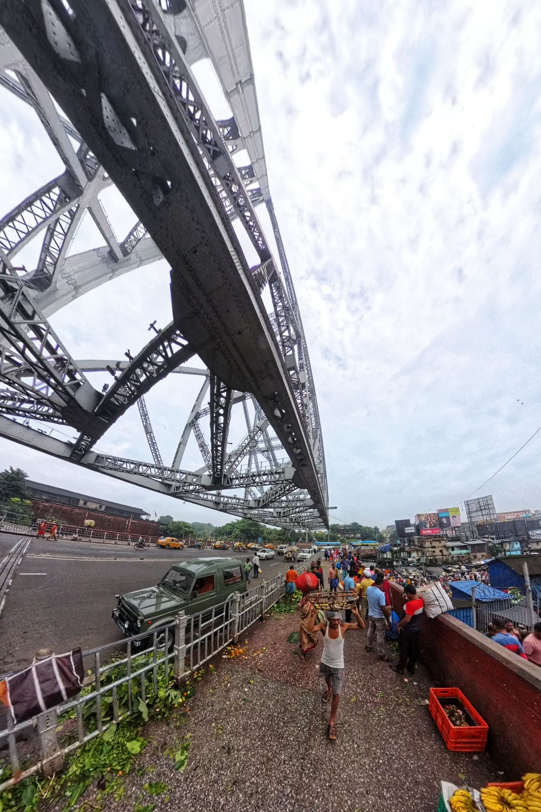 Yellow taxis crossing the steel span of Howrah Bridge in morning haze
